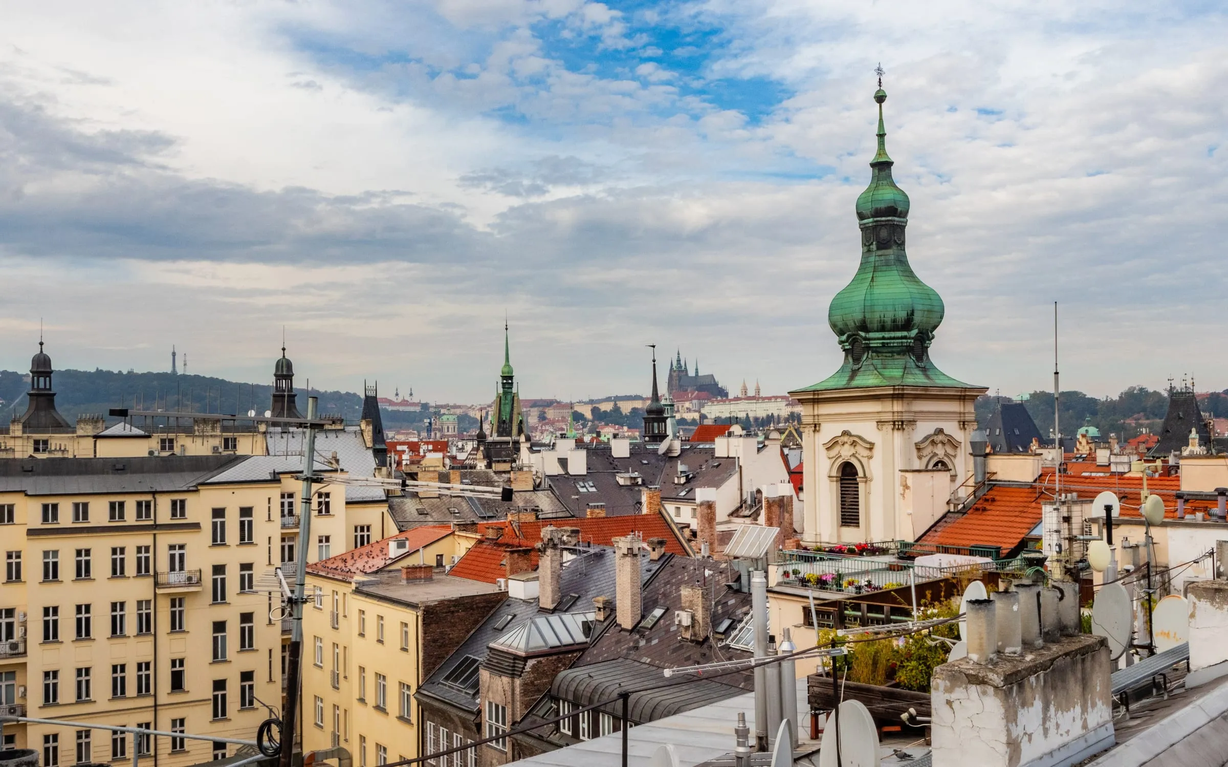 Prague Castle on the horizon behind a green church dome